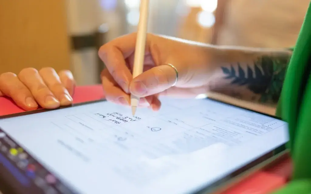 A person uses a stylus to sign a digital document on a tablet